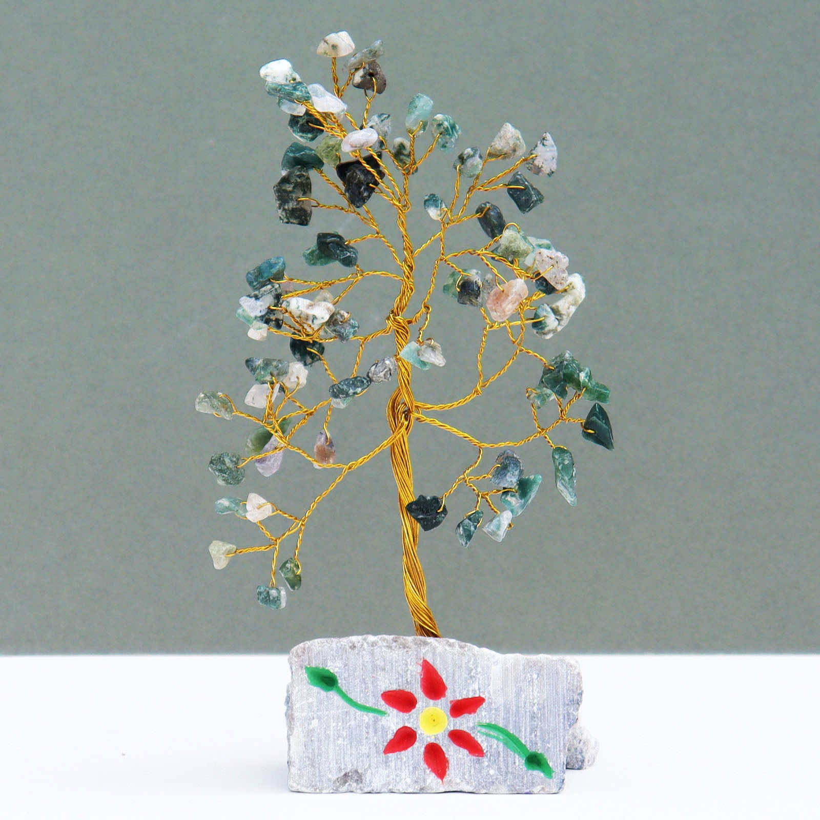 Moss agate tree with 80 natural green gemstone chips on flexible silver wire branches, displayed on a carved and hand-painted stone base from India.


