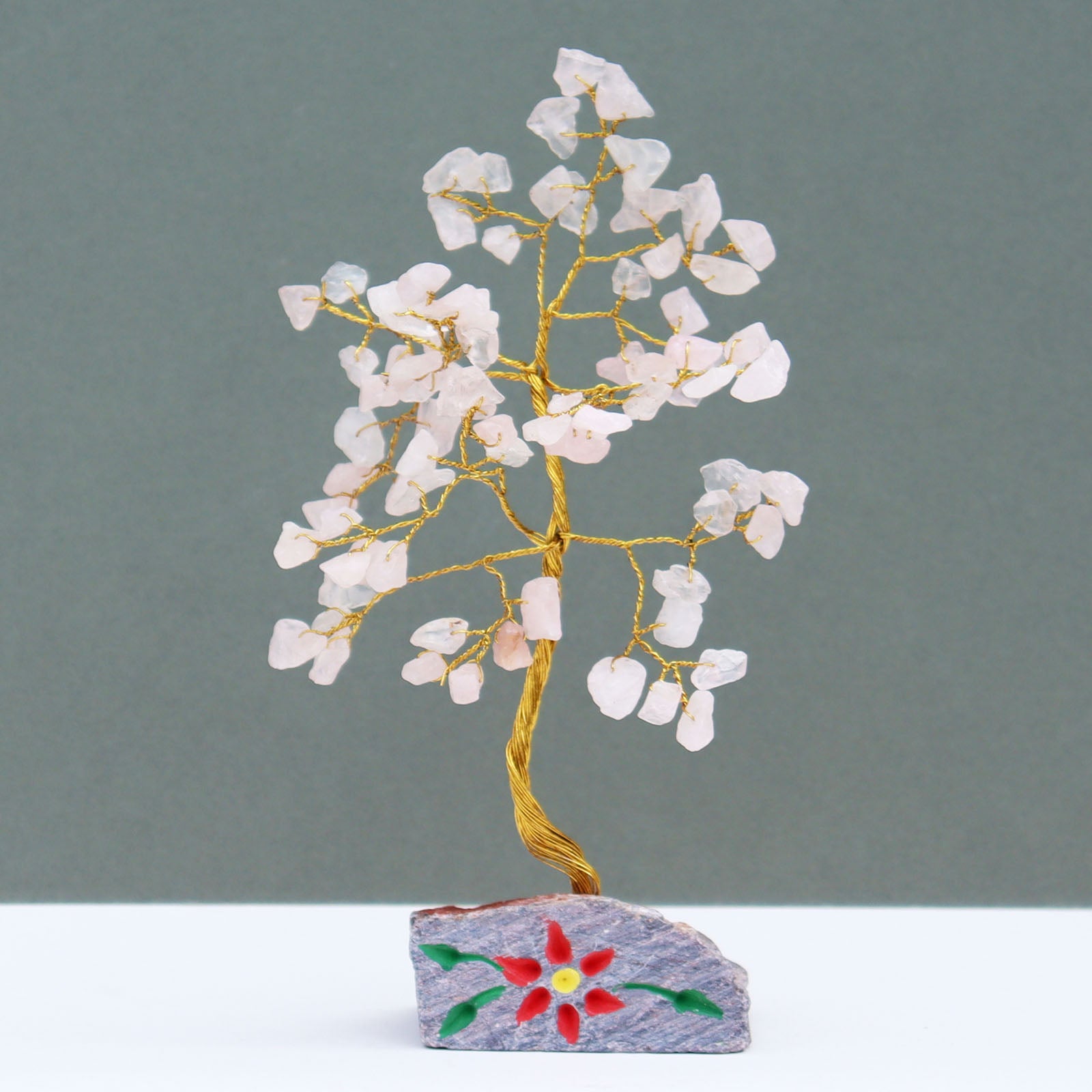 Rose quartz tree with 80 pale pink gemstone chips on silver wire branches, mounted on a hand-carved and painted natural stone base crafted in India.

