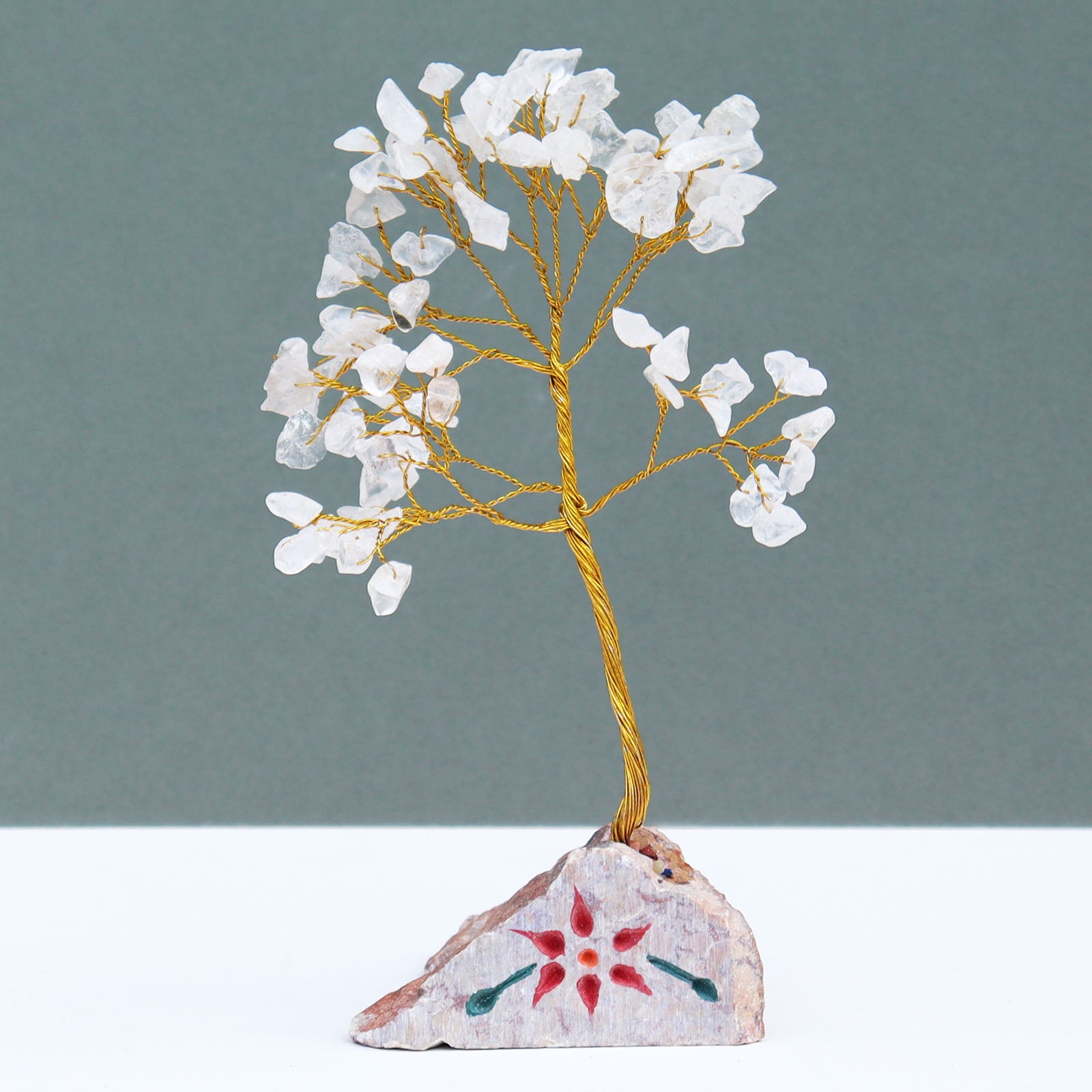 Rock quartz crystal tree with 80 clear gemstone chips on silver wire branches, displayed on a carved and painted natural stone base handcrafted in India.

