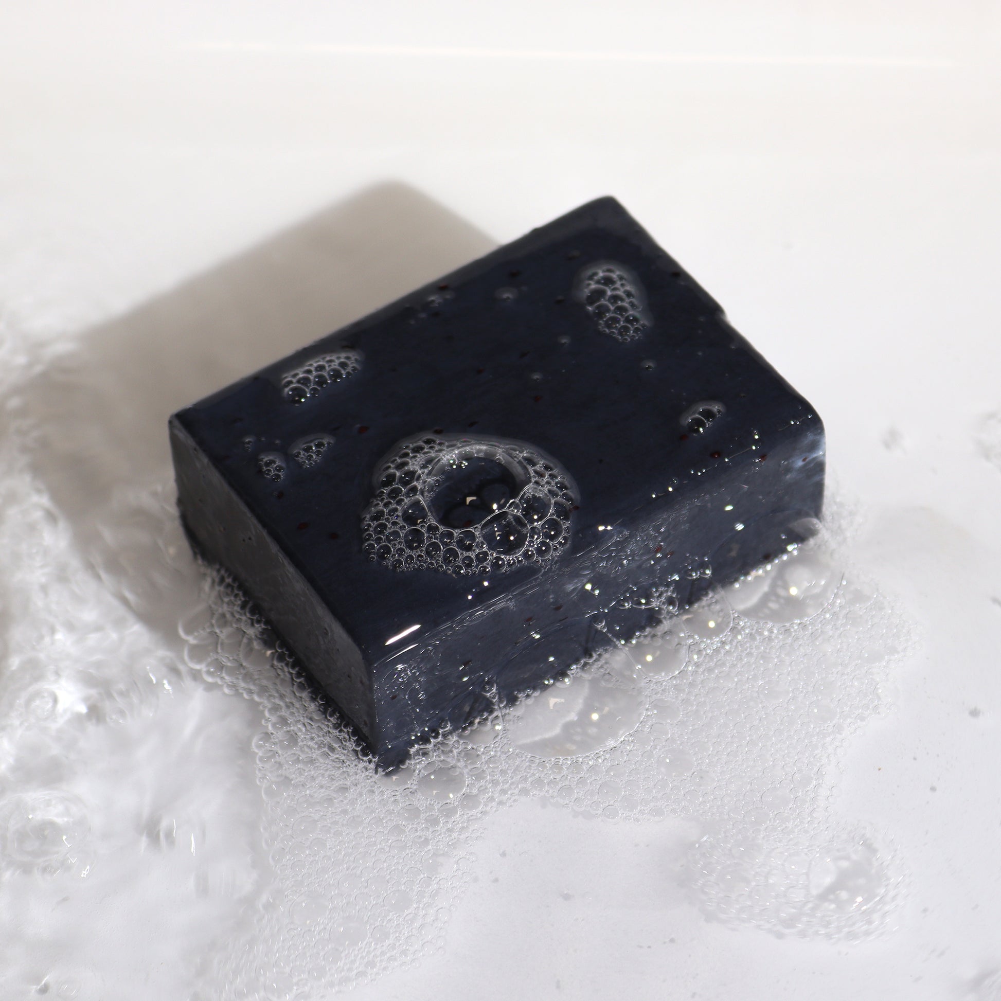 Natural clay soap bar with charcoal, cranberry seeds & sandalwood – detoxifying, exfoliating, and handmade in the UK.

