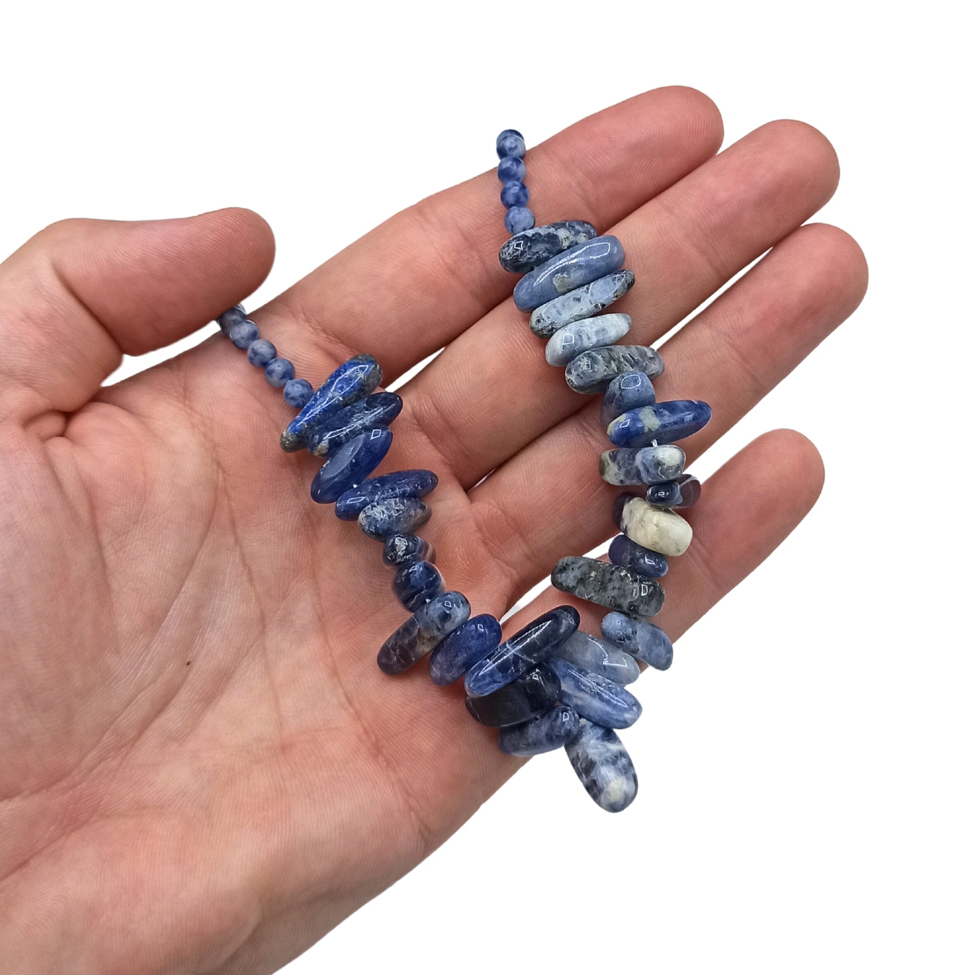 "Longstone Gem Necklace featuring deep blue sodalite gemstone chips and matching round beads, displayed on a hand."
