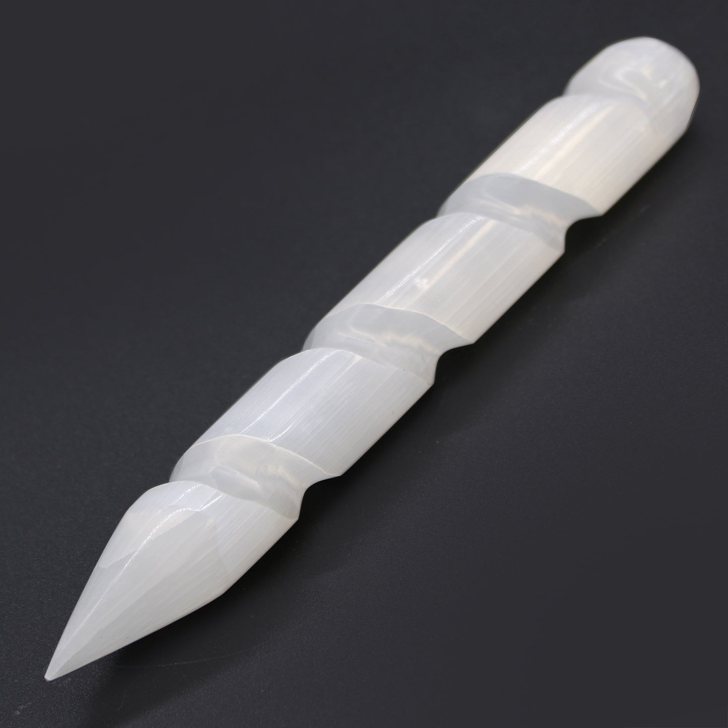 Carved Selenite wand with spiral-grooved body and single pointed tip, hand-cut from Moroccan crystal for energy direction, healing, and spiritual cleansing.

