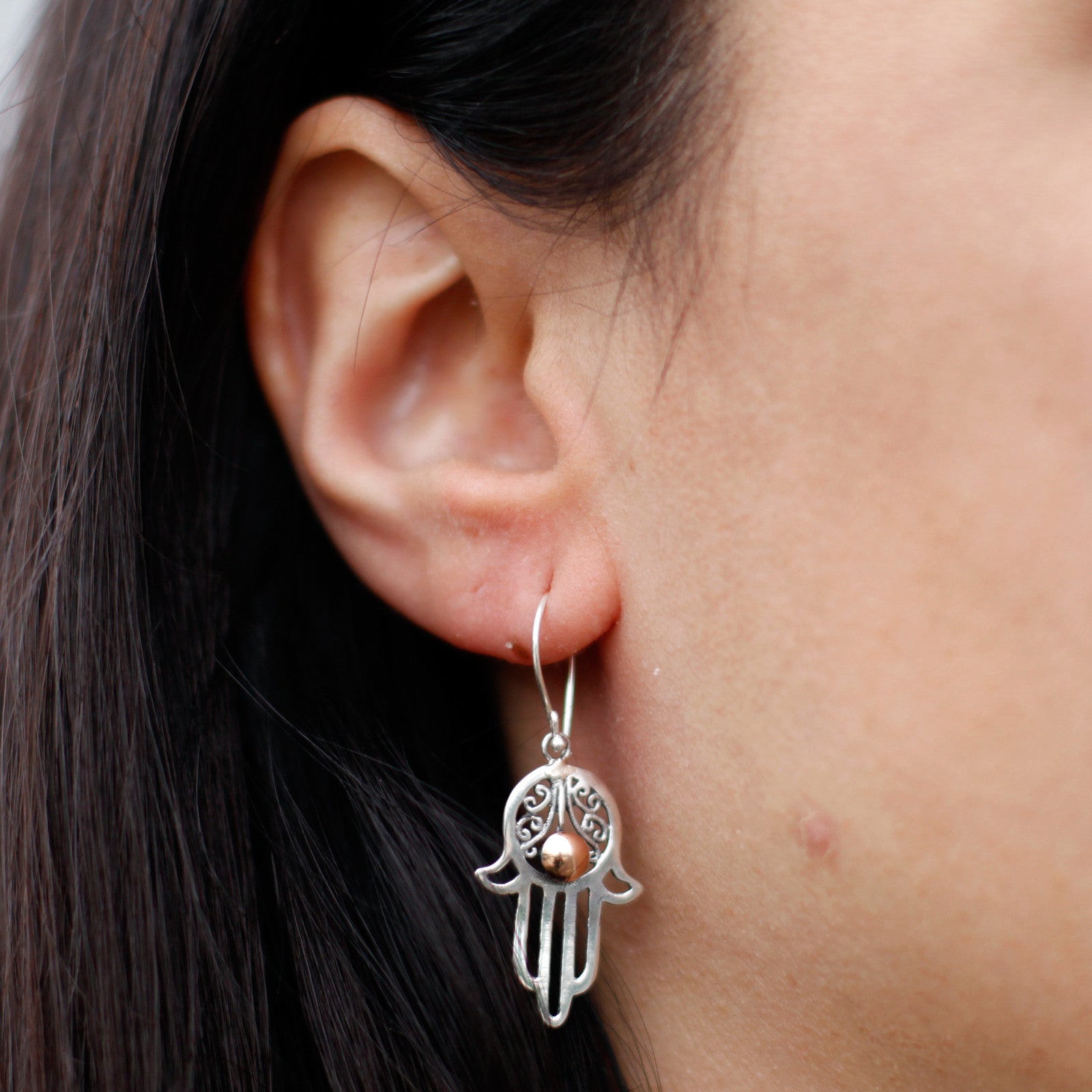 "Hamsa hand earrings in sterling silver with filigree detail and central 18k gold accent, handcrafted in Indonesia."