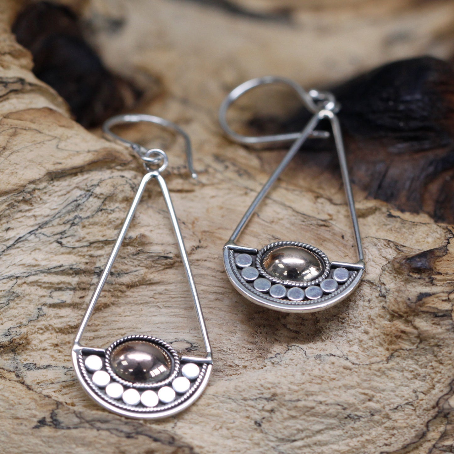 "Geometric silver earrings with balance-scale inspired design and central 18k gold oval, handcrafted in Indonesia."


