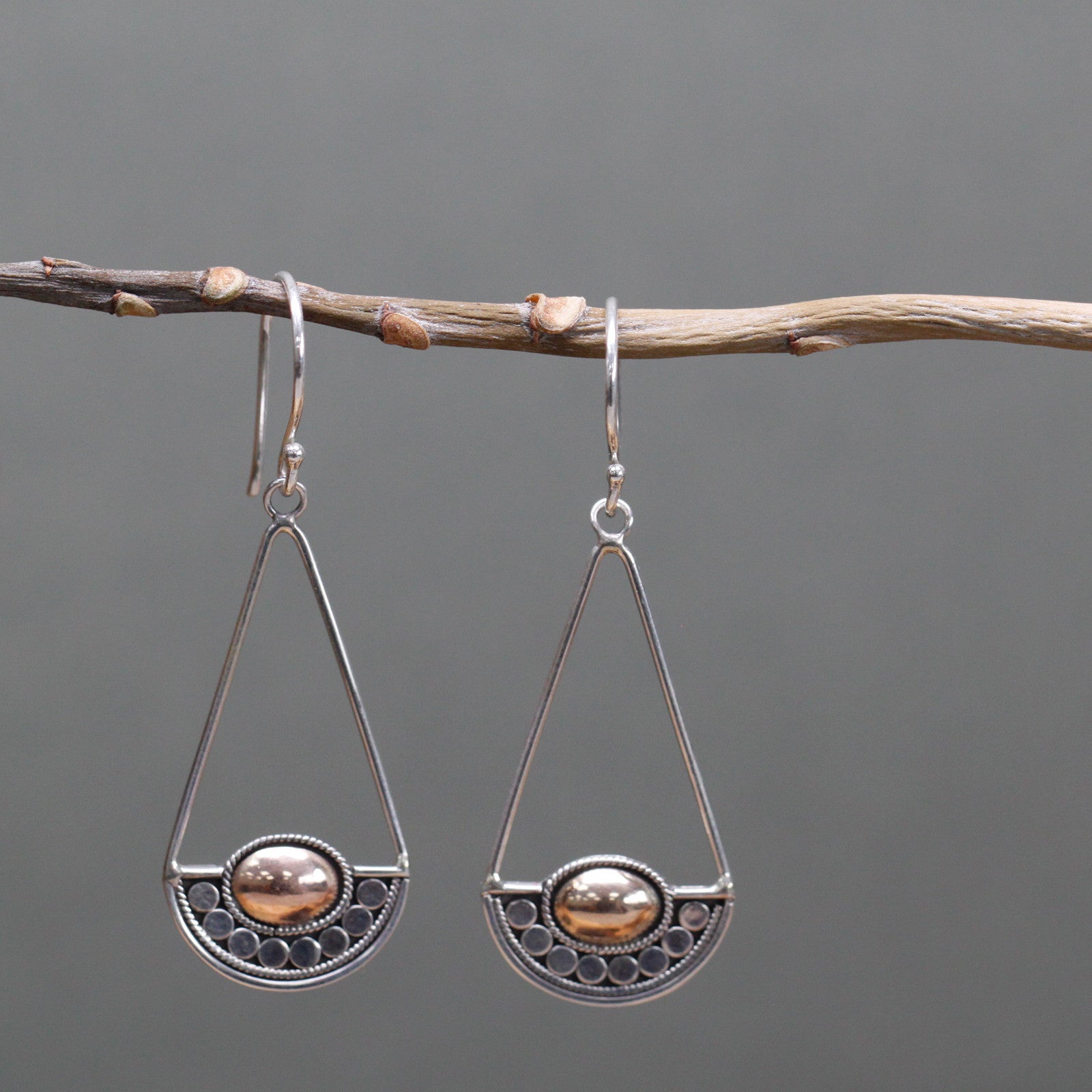"Geometric silver earrings with balance-scale inspired design and central 18k gold oval, handcrafted in Indonesia."