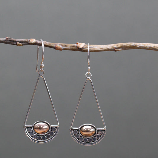 "Geometric silver earrings with balance-scale inspired design and central 18k gold oval, handcrafted in Indonesia."