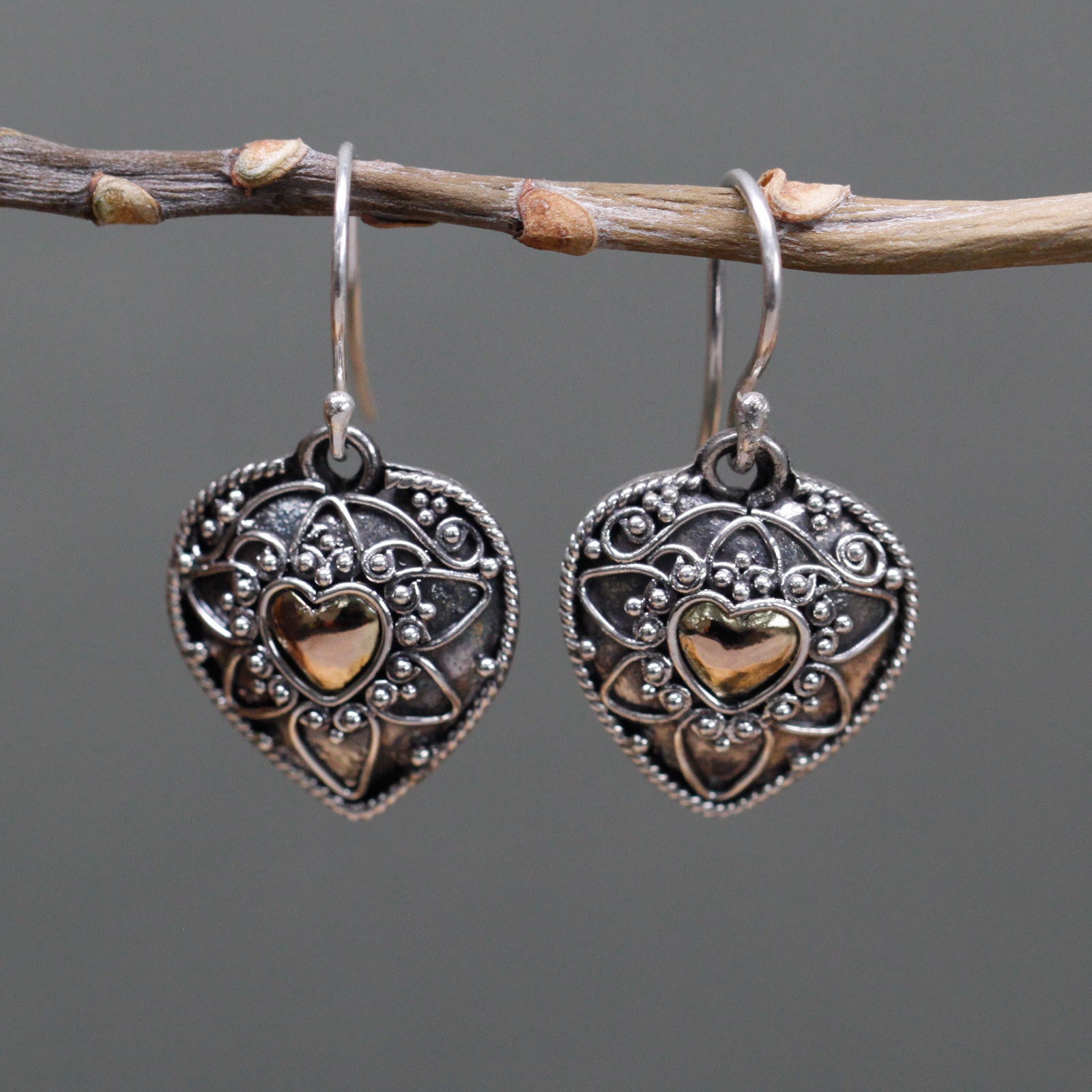 "Heart-shaped sterling silver earrings with mandala design and 18k gold heart centre, handcrafted in Indonesia."