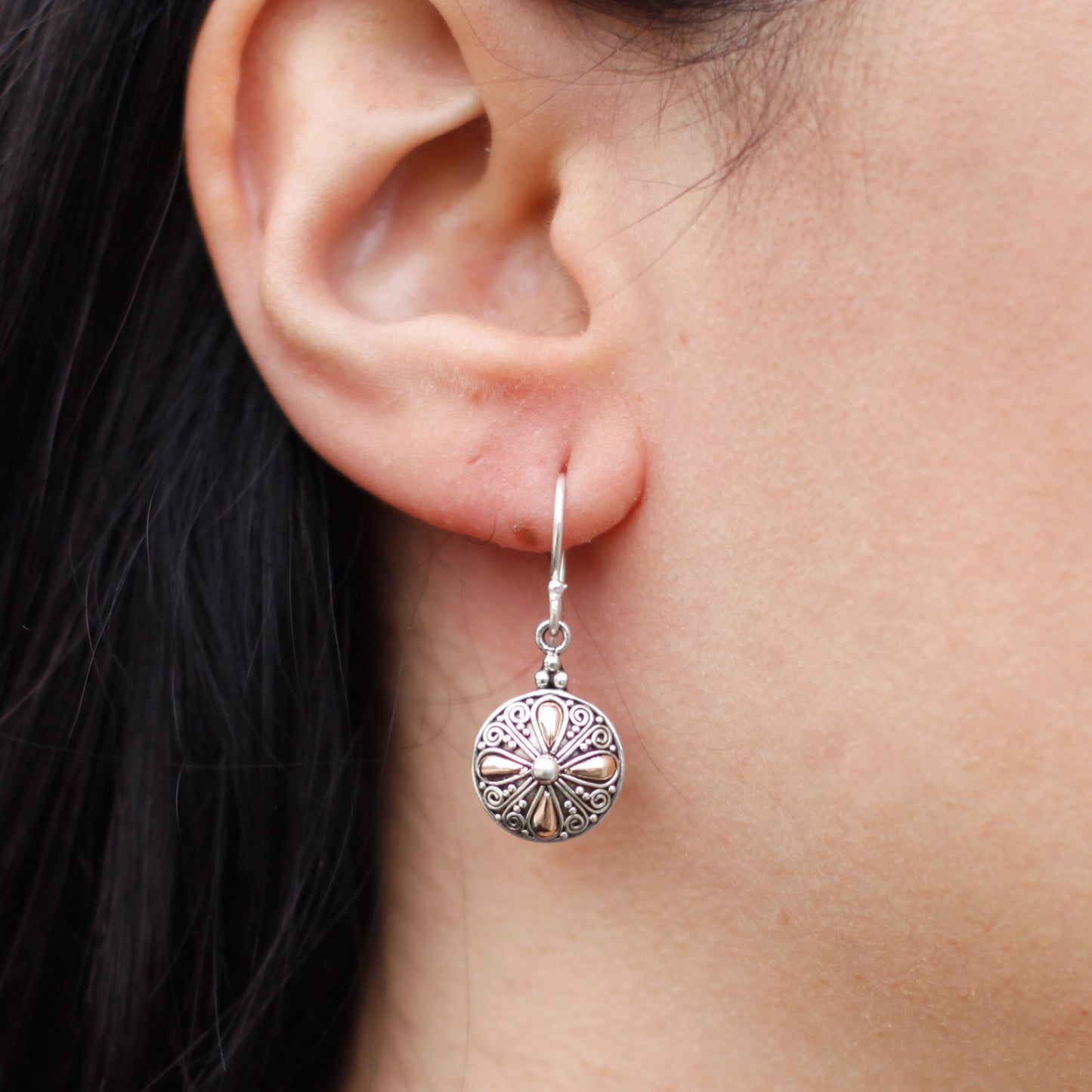 "Round sterling silver earrings with 18k gold teardrop accents and ornate scrollwork, handcrafted in Indonesia."