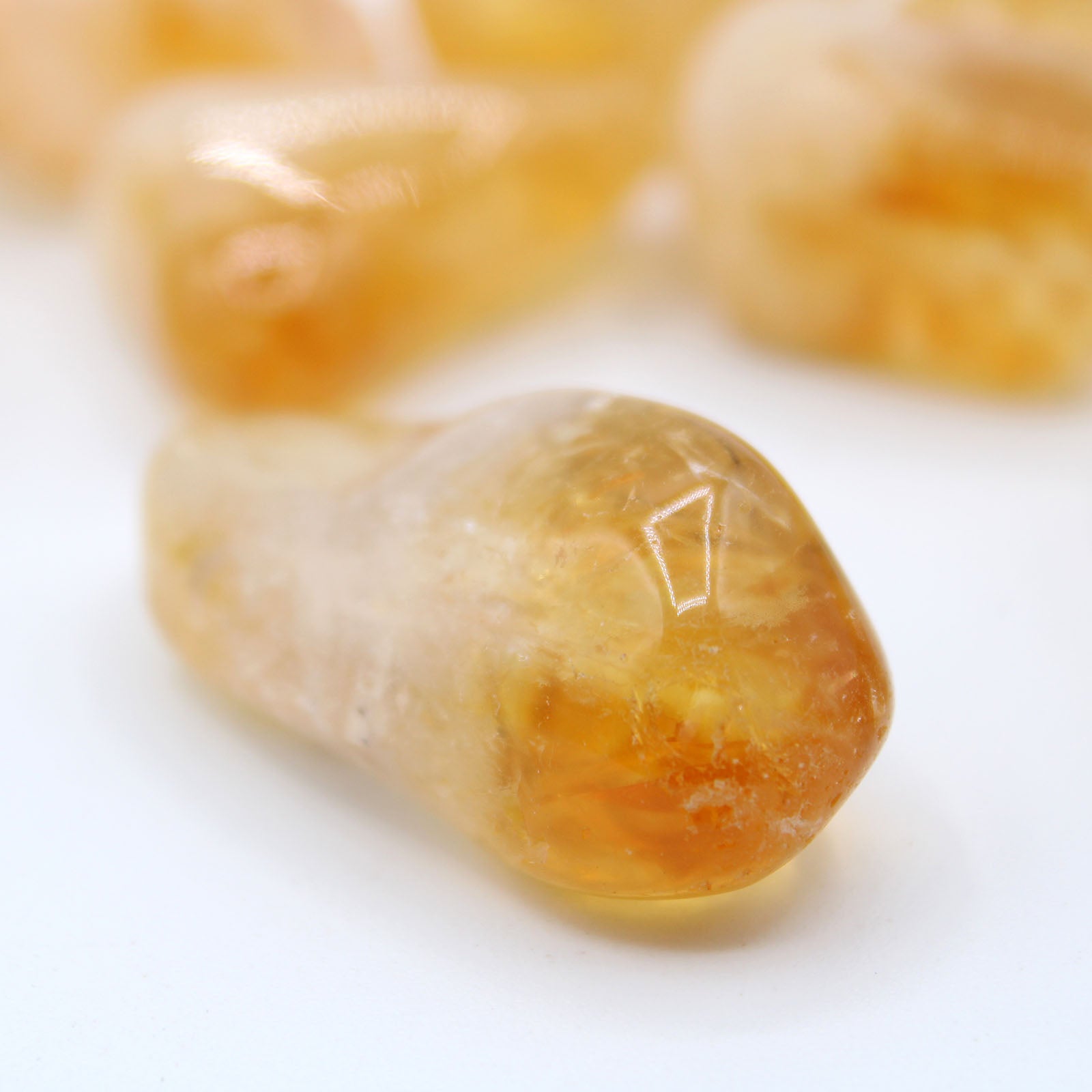 Citrine crystal, polished gemstone, dark yellow to bright yellow in colour on white background